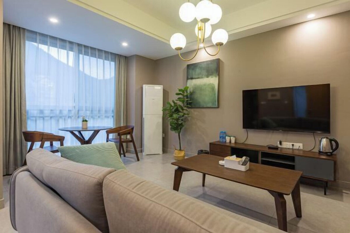 A modern living room with a sofa, a coffee table, a TV, a dining table, and chairs.
