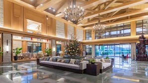A spacious lobby with a high ceiling, wooden beams, a central seating area, and large windows offering views. - Xiuhe Hot Spring Holiday Hotel (Xiushui)