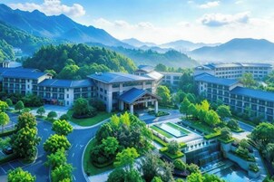 Un moderno complejo hotelero con varias edificaciones, rodeado de exuberante vegetación y montañas al fondo.