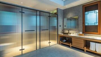 A modern bathroom with a large mirror, a vanity with a sink, and a walk-in shower.