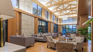 A spacious lobby with high ceilings, large windows, and a variety of seating arrangements including sofas and armchairs. - Xiuhe Hot Spring Holiday Hotel (Xiushui)