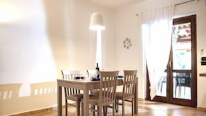 A dining area with a table and chairs, a hanging light fixture, and a door with a view. - Villa with garden - Porto Ada Pizzo - (Pizzo Calabro)