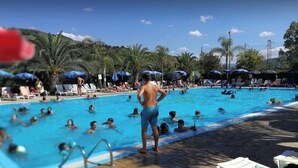 A swimming pool with people in the water and on the poolside, surrounded by umbrellas and lounge chairs. - Villa with garden - Porto Ada Pizzo - (Pizzo Calabro)