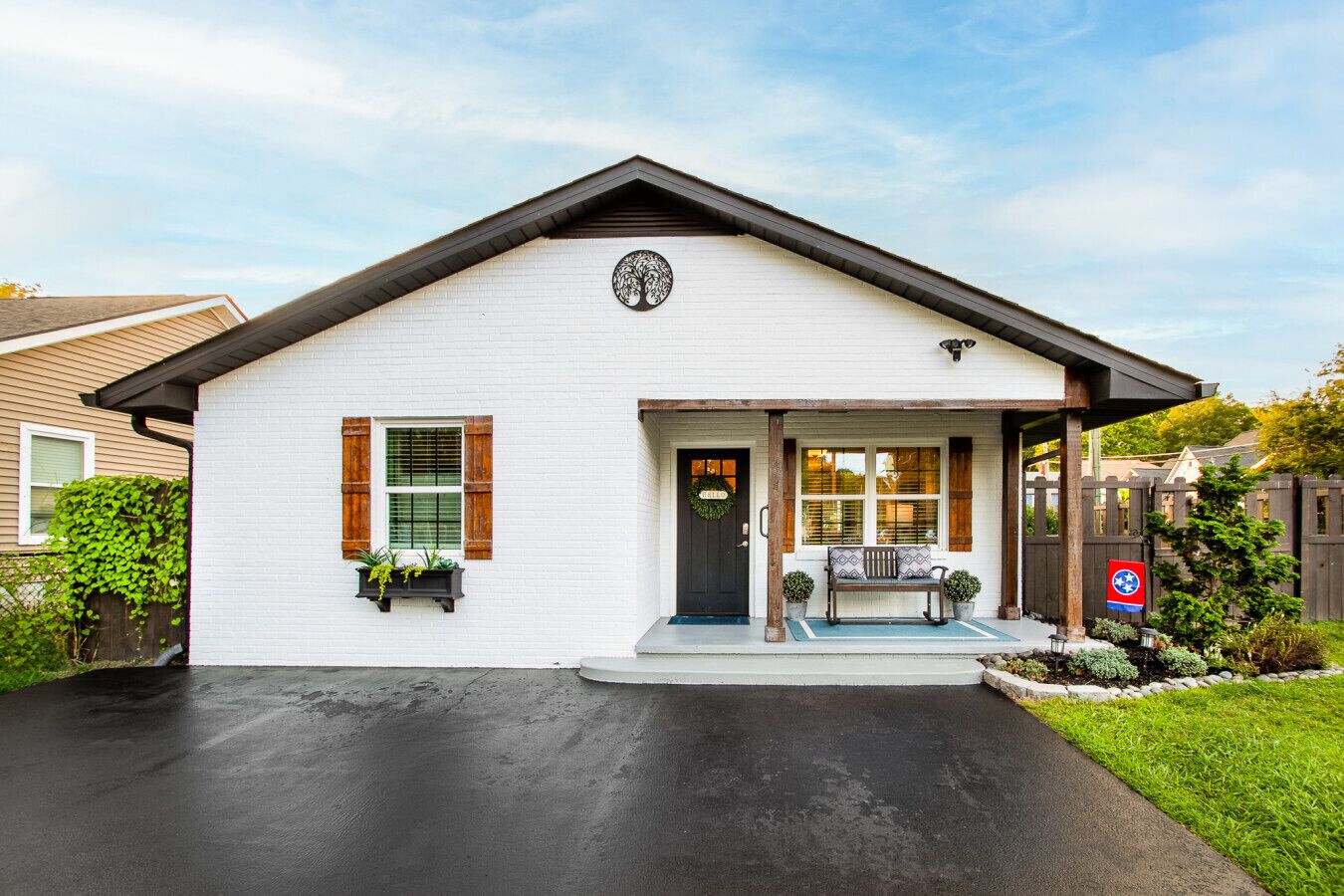 A single-story house with a front porch, a black door, and a small bench.