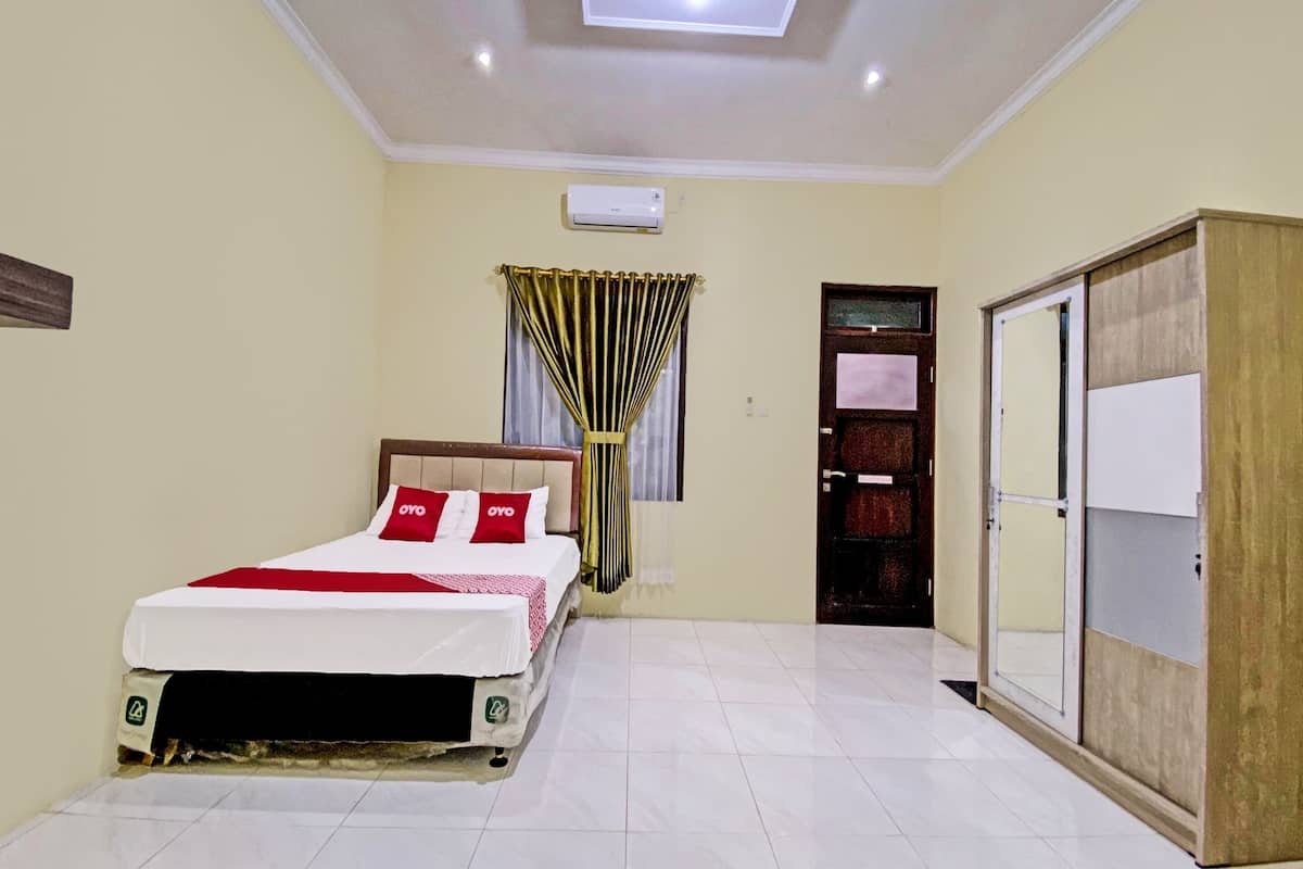 Een slaapkamer met een bed, een airconditioning, een kledingkast en een deur.