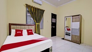 Une chambre d’hôtel avec un lit, une armoire et une fenêtre avec des rideaux.