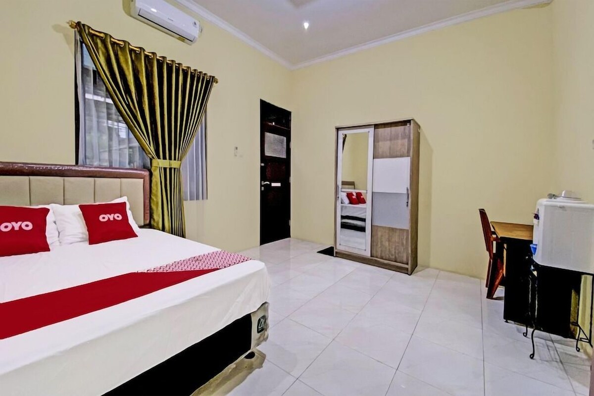 Una habitación de hotel con cama, escritorio, armario y aire acondicionado.