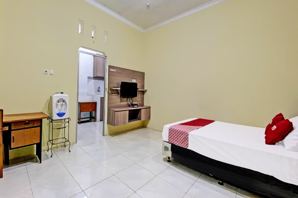 Een hotelkamer met een bed, een bureau, een waterdispenser, een televisie en een kleine kitchenette.