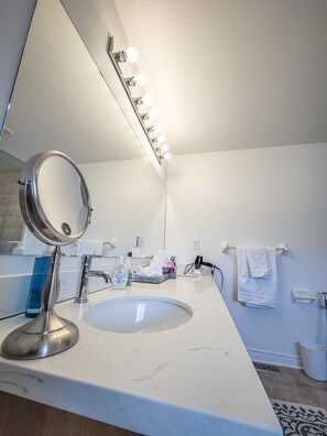 Une salle de bain moderne avec un grand miroir, un meuble-lavabo et un évier.