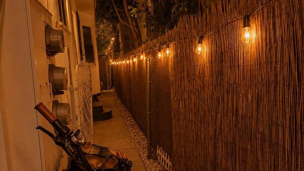 A narrow pathway flanked by a bamboo fence and a building with a bicycle parked beside it. - The Zen Den (Venice)