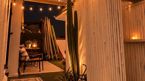 An outdoor patio area with a wooden pergola, string lights, a cactus, and a table with chairs. - The Zen Den (Venice)