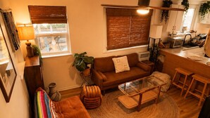 A cozy living room with a sofa, a coffee table, and a dining area with a kitchen in the background. - The Zen Den (Venice)