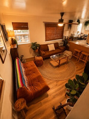 A cozy living room with a sofa, a coffee table, and a dining area with a kitchen in the background. - The Zen Den (Venice)