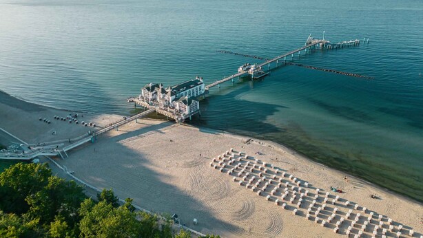 Ein Küstenhotel mit einer ansteigenden Promenade, einem Sandstrand und freiem Blick auf den Ozean.