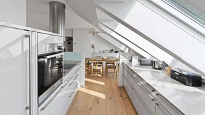 Eine moderne Küche mit großem Fenster, Essbereich und Dunstabzugshaube aus Edelstahl.