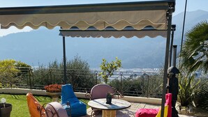 An outdoor patio with a covered seating area, a small table, and a potted plant. - Charming Villa (Saint-Martin-du-Var)
