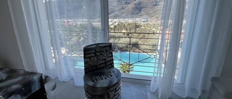 Una habitación con un ventanal grande que da a un paisaje montañoso. Se ve un saco de boxeo negro con la palabra 'TERROR' escrita en primer plano.