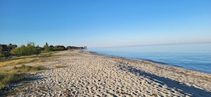 A sandy beach with a clear sky and calm water.