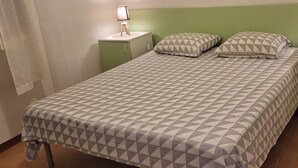 A bed with a geometric patterned bedspread, two bedside lamps, and a green nightstand. - Residence by the sea with private beach access, surrounded by greenery.  (Ghisonaccia)