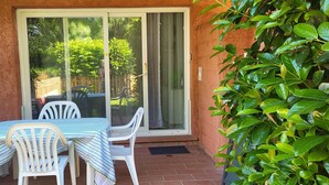 A patio with a table and chairs, a sliding glass door, and a potted plant. - Residence by the sea with private beach access, surrounded by greenery.  (Ghisonaccia)