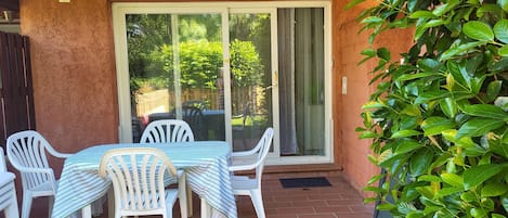 A patio with a table and chairs, a sliding glass door, and a potted plant.