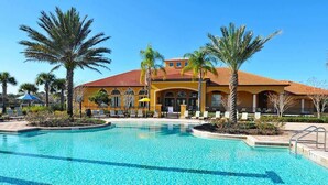 A hotel with a swimming pool, palm trees, and a yellow building with a red roof. - Luxury Villa Near Disney 6 Bd Home with Private Pool and Resort (Davenport)