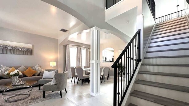 A spacious living area with a staircase leading to an upper floor. - Luxury Villa Near Disney 6 Bd Home with Private Pool and Resort (Davenport)