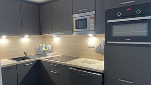 A modern kitchen with grey cabinets, a stainless steel microwave, a built-in oven, and a sink with a faucet. - 150m from ski slopes, 3rd floor, swimming pool, terrace, tv, ski locker, 49m², Gourette (Eaux-Bonnes)