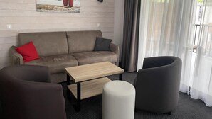 A modern living room with a sofa, a coffee table, and two armchairs. There is a painting on the wall and a window with curtains. - 150m from ski slopes, 3rd floor, swimming pool, terrace, tv, ski locker, 49m², Gourette (Eaux-Bonnes)
