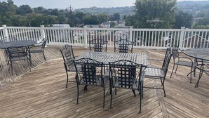 A wooden deck with a metal table and chairs, surrounded by a white railing. - 7th Heaven Guesthouse (Hermann)