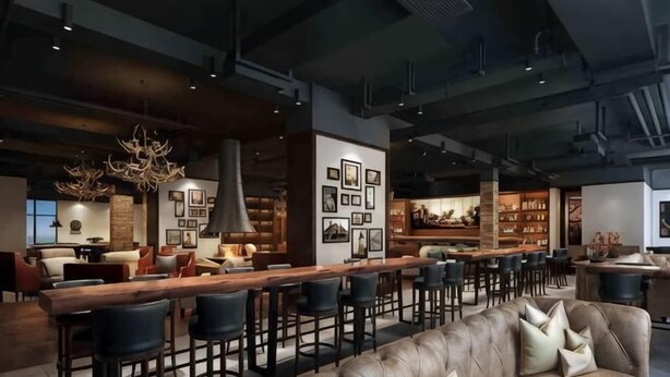 Zona de bar moderna con una barra larga, taburetes y un sofá de cuero.