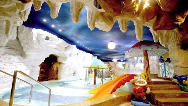 An indoor ice cave with a slide, a small pool, and a figure of a character. - Shuanglong Hotel (Zhangjiakou)