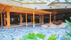 A spacious indoor area with a stone floor, wooden pergola, and a seating area with a fire pit. - Shuanglong Hotel (Zhangjiakou)