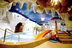 Una cueva de hielo interior con un tobogán, una piscina y una figura de Papá Noel.