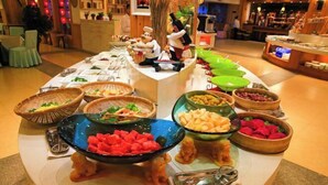 Montaje de bufé con diversos alimentos en cuencos y cestas, un árbol decorativo y una barra con una figura de chef.