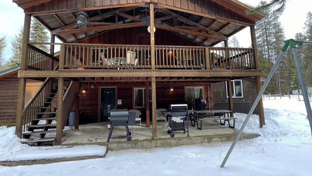 A wooden cabin with a balcony, outdoor seating, and a staircase leading to the entrance.