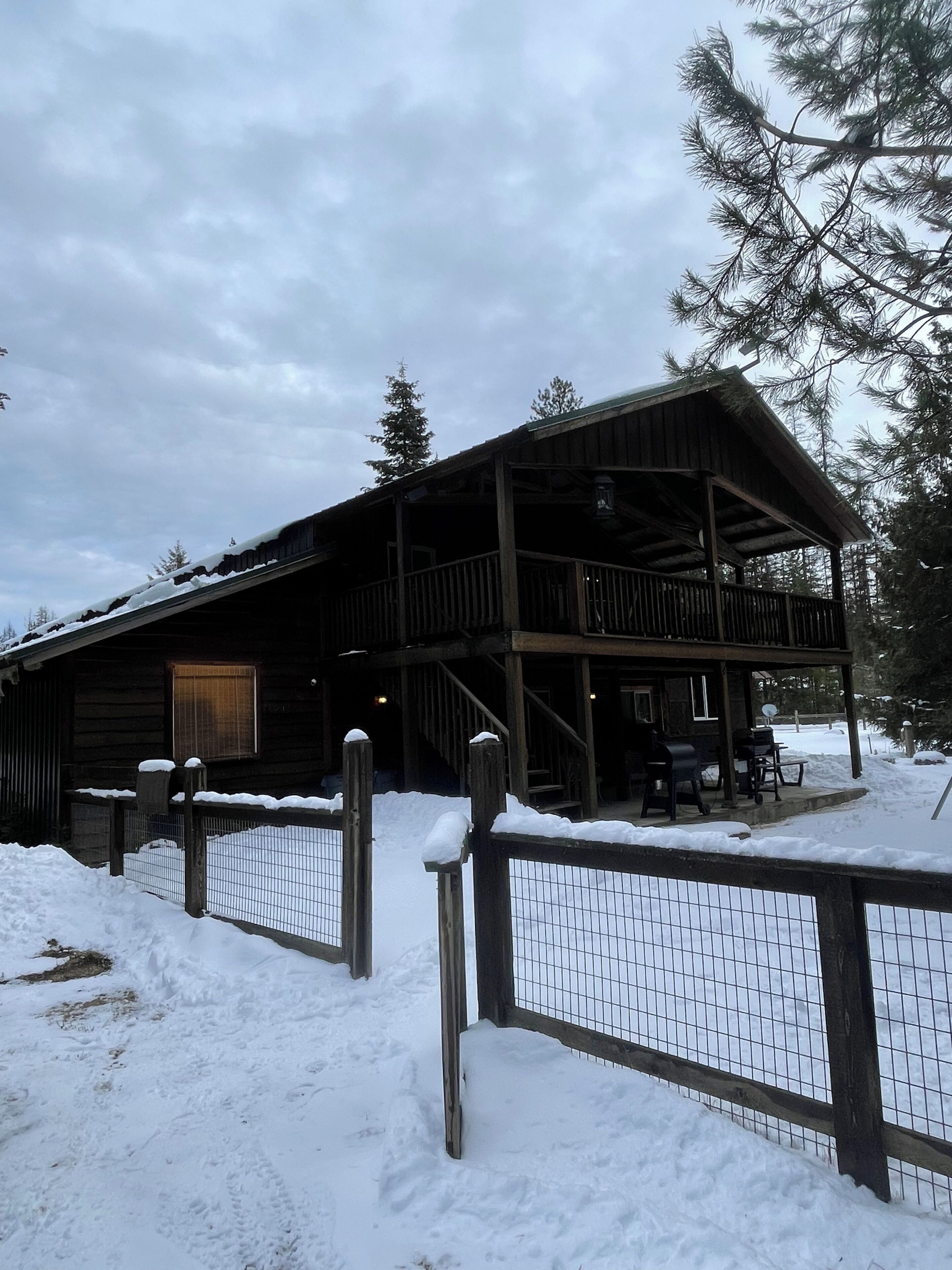 A wooden cabin with a balcony, surrounded by snow.