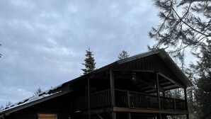 A wooden cabin with a balcony, surrounded by snow.