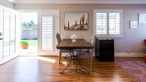 A dining area with a wooden table, chairs, and a black speaker. - Casa Alquimia-Chula Vista Home, Private patio. (Chula Vista)