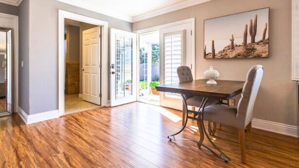 A dining area with a wooden table and chairs, a painting of cacti on the wall, and a view through the open door to the outside. - Casa Alquimia-Chula Vista Home, Private patio. (Chula Vista)
