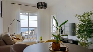 Una sala moderna con una mesa redonda, un sofá, un televisor y un ventanal con vistas.