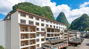A multi-story hotel with balconies, set against a mountainous backdrop. - Vienna Hotel (Guilin)