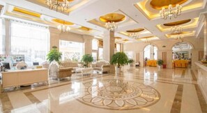 A spacious lobby with a central decorative floor pattern, seating areas, and chandeliers.