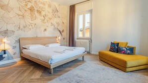 Ein Schlafzimmer mit einem hölzernen Bett, einem gelben Sofa und einer Wand mit einem Blattmuster.