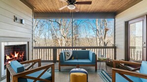 A cozy outdoor seating area with a fireplace, wooden furniture, and a view of trees. - Tims Ford Lake Retreat - The Got-Away (Tullahoma)