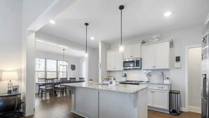 A modern kitchen with white cabinets, a central island, and pendant lighting. - Tims Ford Lake Retreat - The Got-Away (Tullahoma)