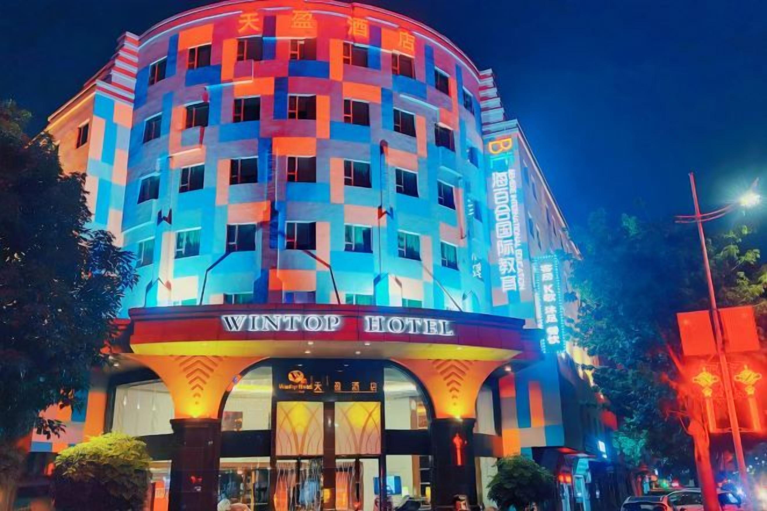 A hotel with a curved facade, a prominent entrance, and illuminated signage.