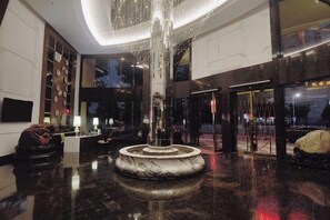 Eine Lobby mit einer zentralen Fontäne, einem Empfangsbereich und einer Sitzecke.