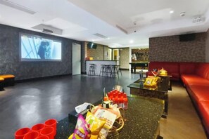 Amplia habitación con zona de bar, asientos y pantalla de proyección.