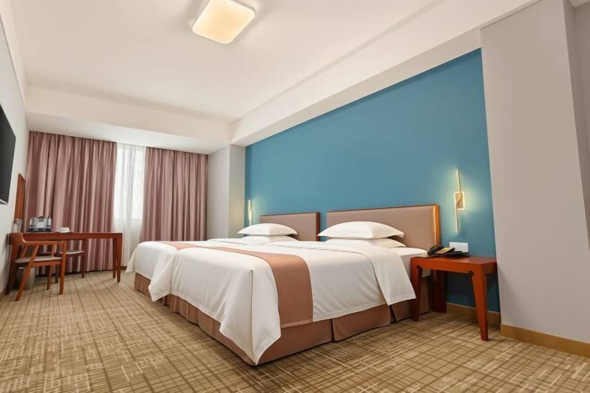 A hotel room with a large bed, a desk, and a chair.